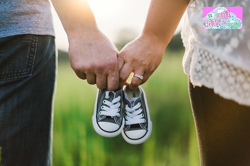 一對戀人牽手並各拿一支童鞋(成一對)，其中一位手指上有戎指。