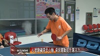 一位穿橘色運動服的心智障礙者在球桌前試著發球