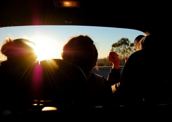 三個人坐在車廂內的剪影，前方陽光耀眼