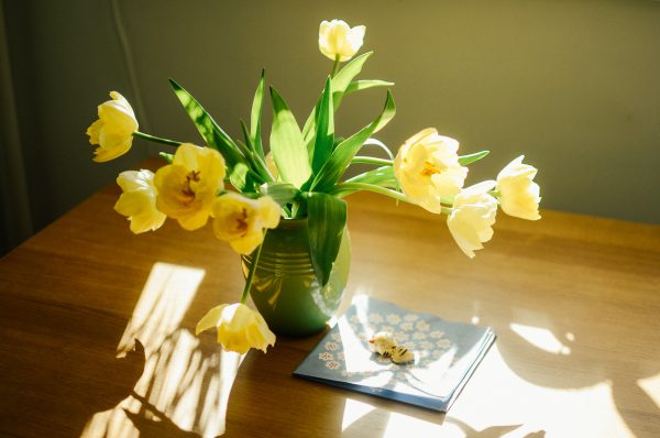一支綠色花瓶裏插滿了小黃花，花瓶旁並有一條手帕，不及小貓的飾品
