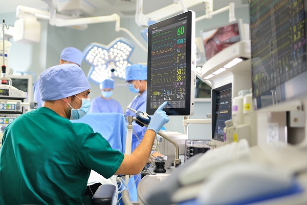 手術房裏一位醫師指著心跳儀器的螢幕。另外後頭還有3位醫療人員