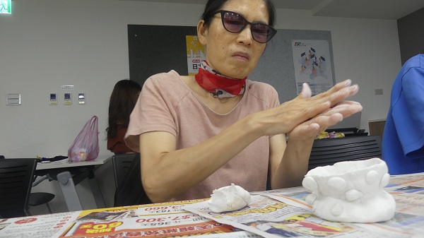一位視障的女性長者正在捏黏土